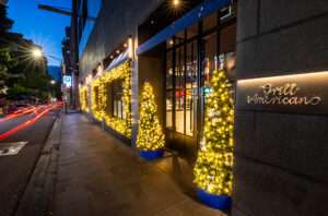 Time lapse close up of exterior of Grill Americano in Flinders Lane with traditional Christmas garlands and glowing lights, and two Christmas trees at front door.