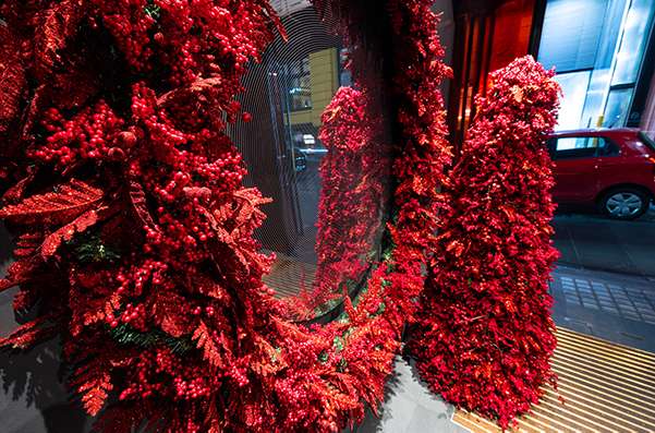 A Red berry Christmas tree shape and large red berry wreath hanging in Foyer of city building.