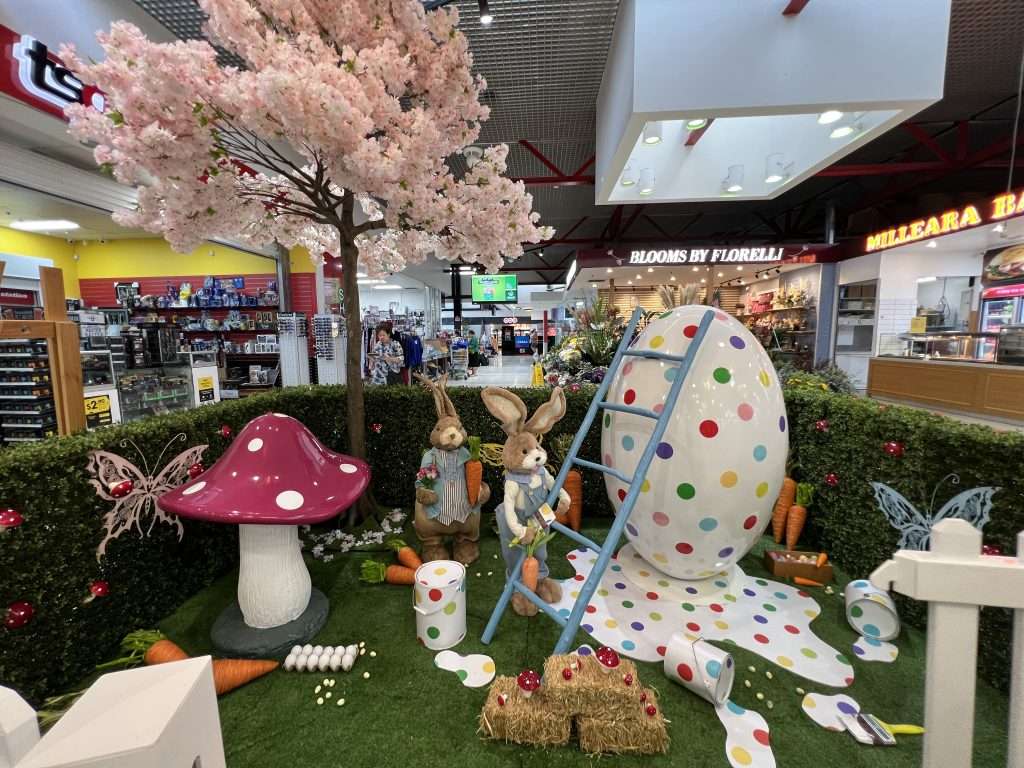 Easter display with large egg being painted by raffia bunnies.