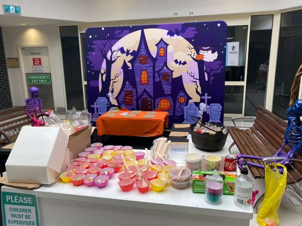 Cookie decorating supplies are laid out before a purple haunted castle graphic wall