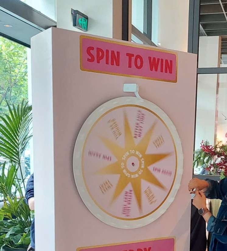 A pink spinner device reads Spin To Win. A gold star is in the centre. We can see the hands of the person who has spun it.