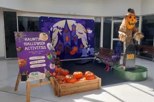 Halloween shopping centre display featuring jack-o'-lantern scarecrow, purple haunted castle graphic and pumpkins