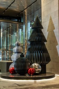 Large charcoal paper honeycomb Christmas trees on a black base with lighting in a foyer