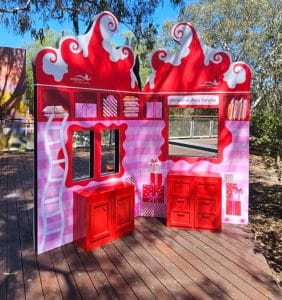 A pink and red Christmas playhouse sitting in a piazza in Werribee decorated in a grinch inspired theme