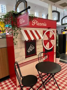 3D custom display built to look like a Pizzeria with spin to win wheel and cafe seating out front.