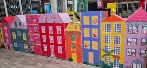 Closeup of a small playspace with coloured houses. Housees are in colours orange, pink, yellow and purple.