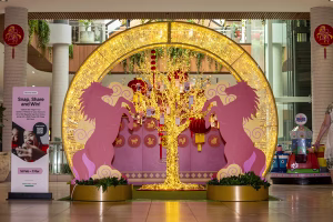 A Lunar New Year display framed by a golden LED arch with 2 2D horse images. There is a wishing tree in the middle of the arch.