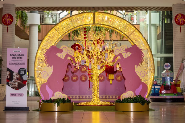 A Lunar New Year display framed by a golden LED arch with 2 2D horse images. There is a wishing tree in the middle of the arch.