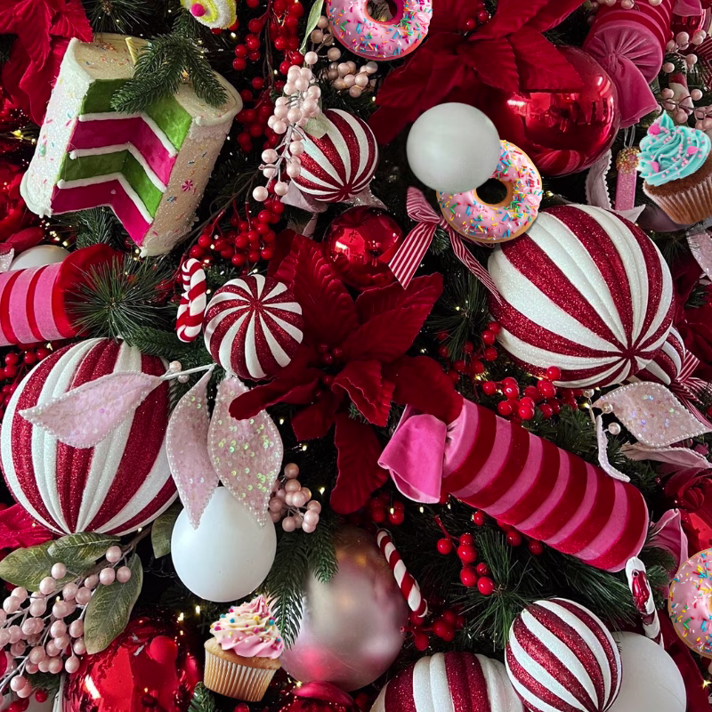 Christmas tree closeup showing candy themed decorations in red and white plus colourful cakes and sweets.