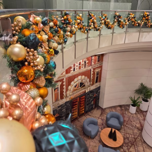 A close up a of beautiful Chrsitmas garland decorated in teal, gold and copper. The garland is looped around a commercial building balcony.
