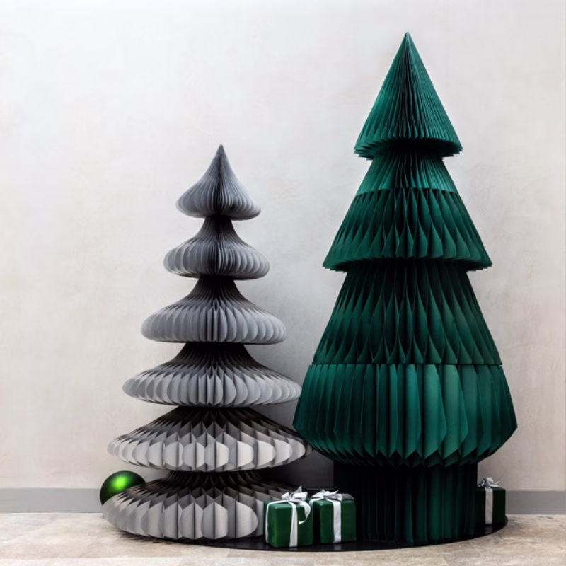 Twohoneycomb paper Christmas trees on a black board. The trees are in silver and dark green