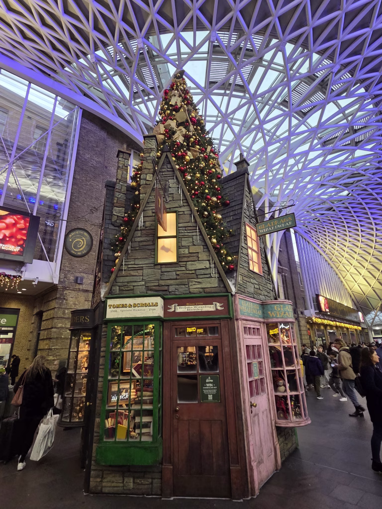Large Christmast tree themed as books and scrolls business from Harry Potter movies. Standing in Kings Cross station main casueway