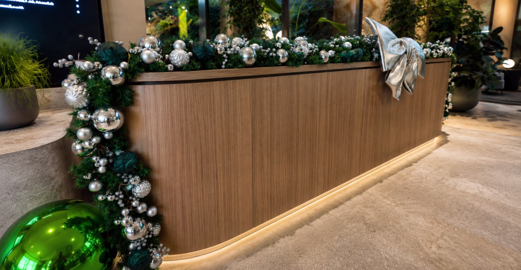 Christmas garland draped along a reception desk. Decorated in teal green and silver with large bow