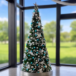 A pre-decorated commercial Christmas tree display styled with blue and silver baubles, silver berry picks, frosted flowers, and silver topper.